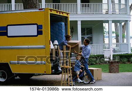 Stock Image - Mid adult couple unloading cardboard boxes from a moving van. Fotosearch