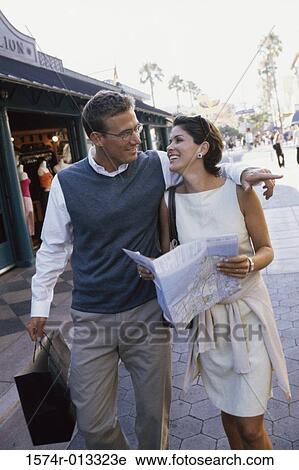 Stock Image - Mid adult couple walking in a market. Fotosearch