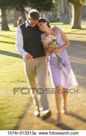 Mid adult couple walking together on a lawn View Large Photo Image Stock Image - Mid adult couple walking together on a lawn. Fotosearch