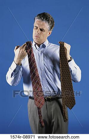 Mid adult man deciding on a neck tie View Large Photo Image Stock Image - Mid adult man deciding on a neck tie. Fotosearch
