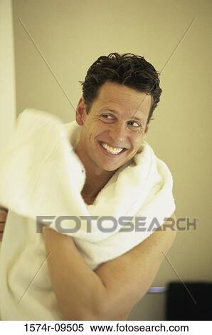 Stock Photography - Mid adult man smiling while drying his face with a towel. Fotosearch