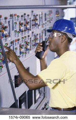 Mid adult man standing in the control room talking on a walkie-talkie View Large Photo Image Stock Photography - Mid adult man standing in the control room talking on a walkie-talkie. Fotosearch