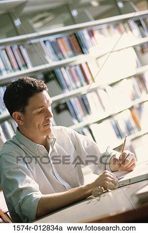 Mid adult man studying in a library View Large Photo Image Stock Image - Mid adult man studying in a library. Fotosearch