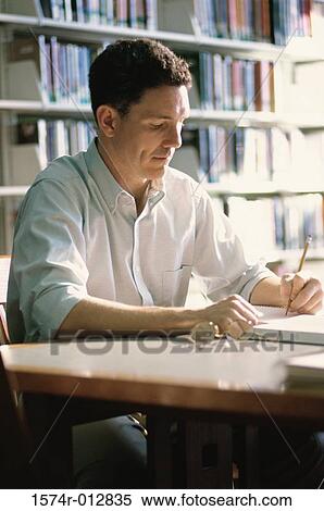 Stock Photography - Mid adult man studying in a library. Fotosearch