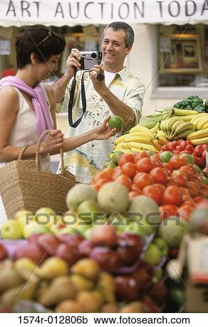 Stock Image - Mid adult man taking a photograph of a mid adult woman. Fotosearch