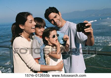Mid adult man taking a photograph of his family View Large Photo Image Stock Image - Mid adult man taking a photograph of his family. Fotosearch