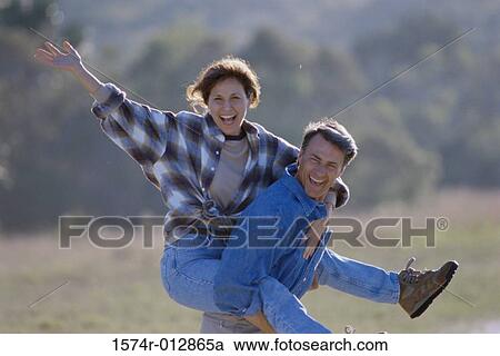 Mid adult woman riding piggyback on a mid adult man View Large Photo Image Stock Image - Mid adult woman riding piggyback on a mid adult man. Fotosearch