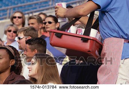 Mid section view of a vendor selling drinks to spectators in a stadium View Large Photo Image Picture - Mid section view of a vendor selling drinks to spectators in a stadium. Fotosearch