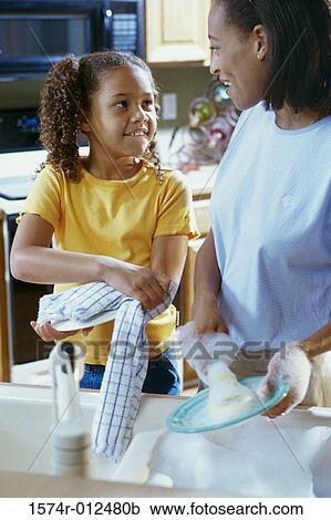 Stock Image - Mother and daughter drying dishes in the kitchen. Fotosearch
