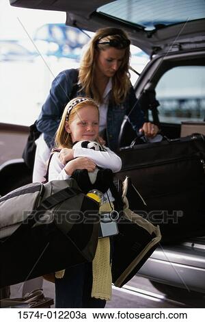 Stock Image - Mother and daughter loading luggage into the back of a car. Fotosearch