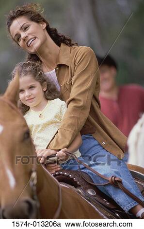 Stock Image - Mother and daughter riding a horse. Fotosearch