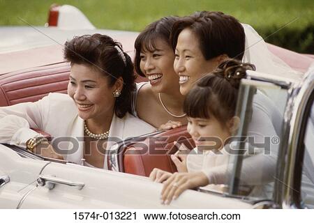 Stock Image - Mother sitting in a convertible car with her two daughters and a bridesmaid. Fotosearch