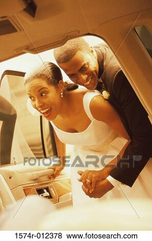 Newlywed couple looking inside of a car View Large Photo Image Stock Photo - Newlywed couple looking inside of a car. Fotosearch