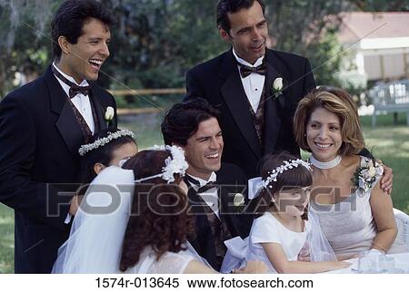 Stock Photography - Newlywed couple sitting with their parents and wedding guests. Fotosearch