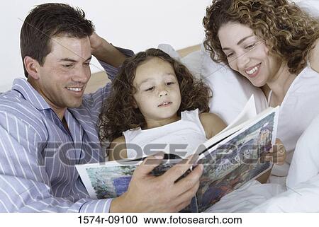 Parents and their daughter lying in bed together reading a book View Large Photo Image Stock Image - Parents and their daughter lying in bed together reading a book. Fotosearch