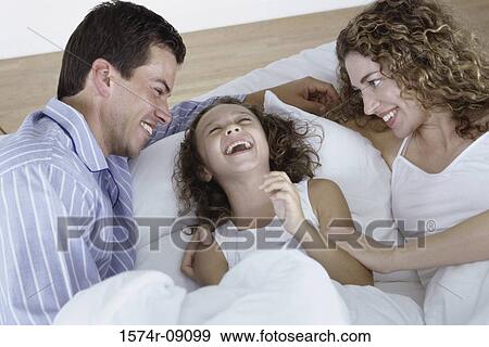 Parents and their daughter lying in bed together View Large Photo Image Stock Photo - Parents and their daughter lying in bed together. Fotosearch