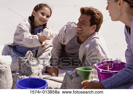 Parents and their daughter making a sand castle on the beach View Large Photo Image Stock Image - Parents and their daughter making a sand castle on the beach. Fotosearch