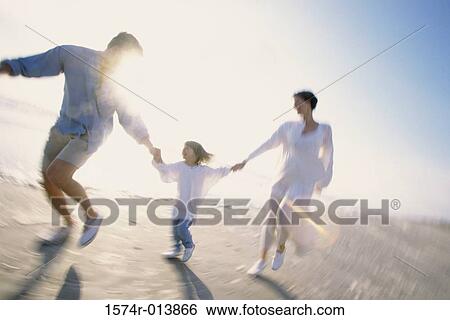 Stock Photograph - Parents and their daughter running on the beach. Fotosearch