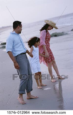Parents and their daughter standing on the beach View Large Photo Image Picture - Parents and their daughter standing on the beach. Fotosearch