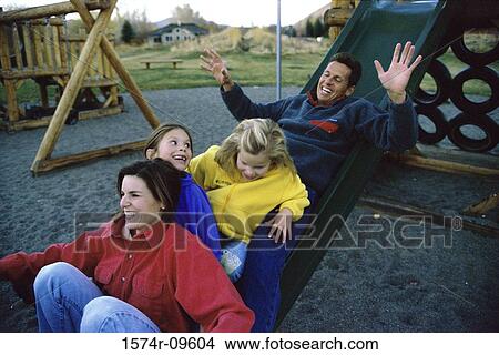 Picture - Parents and their two daughters playing on a slide. Fotosearch