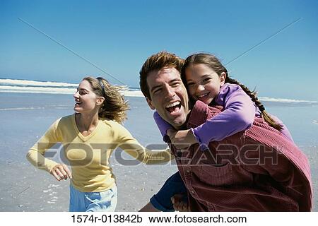 Stock Image - Parents playing with their daughter on the beach. Fotosearch