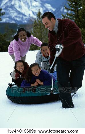 Stock Image - Parents pulling their children on an inflatable ring. Fotosearch