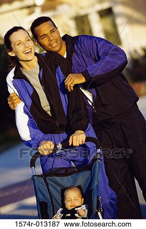 Parents strolling with their daughter in a baby stroller View Large Photo Image Stock Photo - Parents strolling with their daughter in a baby stroller. Fotosearch