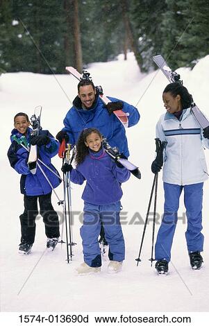 Stock Image - Parents walking with their two children in snow. Fotosearch