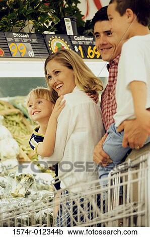 Stock Image - Parents with their two children standing in a supermarket. Fotosearch