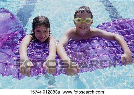 Stock Image - Portrait of a boy and a girl leaning on a pool raft in a swimming pool. Fotosearch