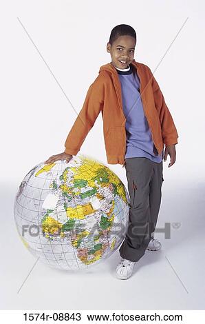 Portrait of a boy standing leaning against an inflatable globe View Large Photo Image Stock Image - Portrait of a boy standing leaning against an inflatable globe. Fotosearch