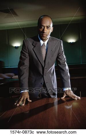 Stock Image - Portrait of a businessman leaning against a table. Fotosearch
