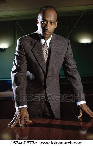 Portrait of a businessman leaning against a table View Large Photo Image Stock Image - Portrait of a businessman leaning against a table. Fotosearch