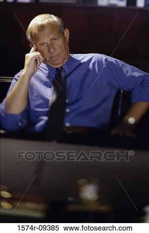 Portrait of a businessman seated behind an office desk View Large Photo Image Stock Photography - Portrait of a businessman seated behind an office desk. Fotosearch