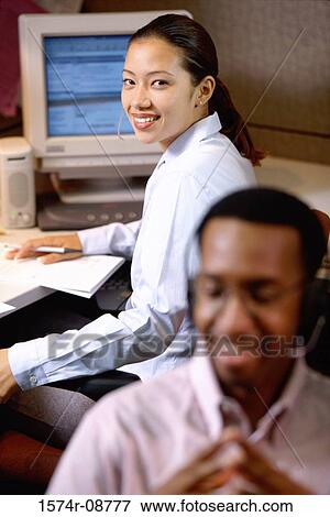 Portrait of a businesswoman looking back with a businessman sitting in front of her View Large Photo Image Stock Photo - Portrait of a businesswoman looking back with a businessman sitting in front of her. Fotosearch