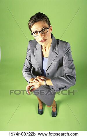 Stock Image - Portrait of a businesswoman standing touching her wristwatch. Fotosearch