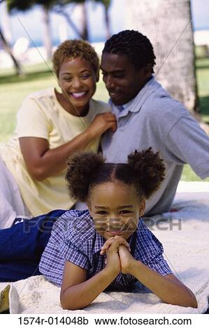 Stock Image - Portrait of a daughter smiling with her parents sitting behind her. Fotosearch
