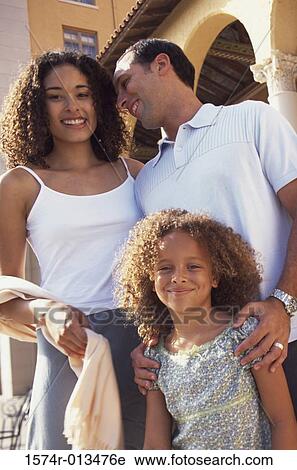 Stock Image - Portrait of a daughter standing with her parents. Fotosearch