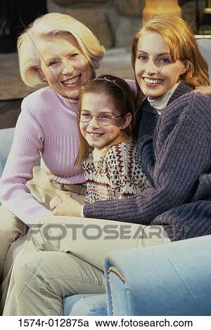 Portrait of a daughter with her mother and grandmother sitting on a couch in a living room View Large Photo Image Stock Image - Portrait of a daughter with her mother and grandmother sitting on a couch in a living room. Fotosearch
