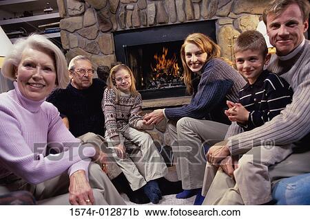 Stock Image - Portrait of a family sitting near the fireplace in a living room. Fotosearch