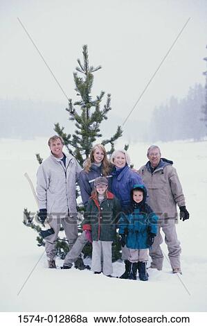Portrait of a family standing in front of a Christmas tree in snow View Large Photo Image Stock Image - Portrait of a family standing in front of a Christmas tree in snow. Fotosearch