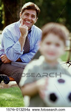 Portrait of a father sitting with a laptop looking at his son View Large Photo Image Stock Image - Portrait of a father sitting with a laptop looking at his son. Fotosearch