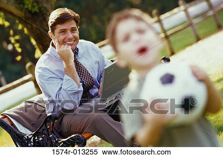 Portrait of a father sitting with a laptop looking at his son View Large Photo Image Stock Photography - Portrait of a father sitting with a laptop looking at his son. Fotosearch