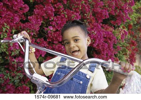 Stock Image - Portrait of a girl holding the handlebars of a bicycle. Fotosearch