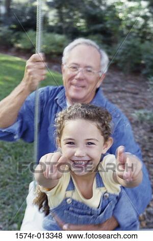 Portrait of a granddaughter sitting on her grandfather's lap swinging on a swing View Large Photo Image Stock Photo - Portrait of a granddaughter sitting on her grandfather's lap swinging on a swing. Fotosearch