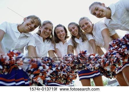 Stock Image - Portrait of a group of cheerleaders holding pom-poms. Fotosearch