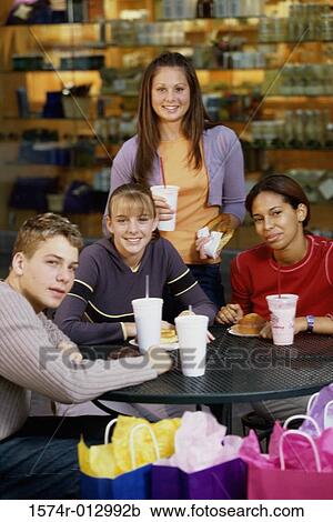 Stock Image - Portrait of a group of teenagers sitting in a shopping mall restaurant. Fotosearch