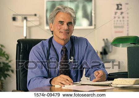 Portrait of a male doctor seated behind a desk View Large Photo Image Stock Photo - Portrait of a male doctor seated behind a desk. Fotosearch