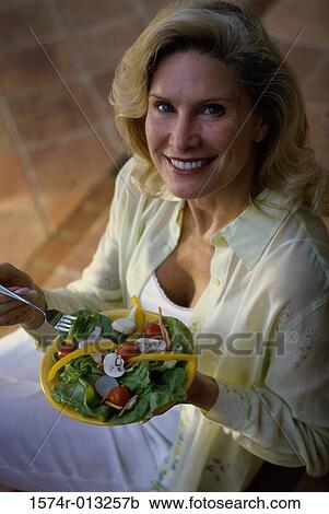 Stock Image - Portrait of a mature woman holding a plate of salad. Fotosearch