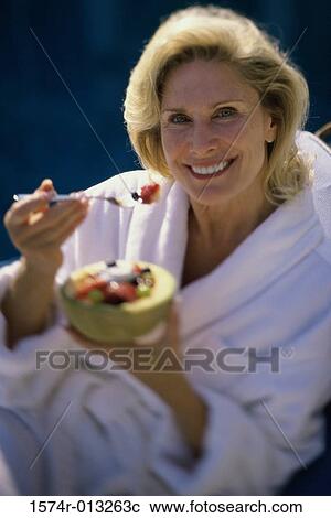 Stock Image - Portrait of a mature woman holding a bowl of fruit salad. Fotosearch
